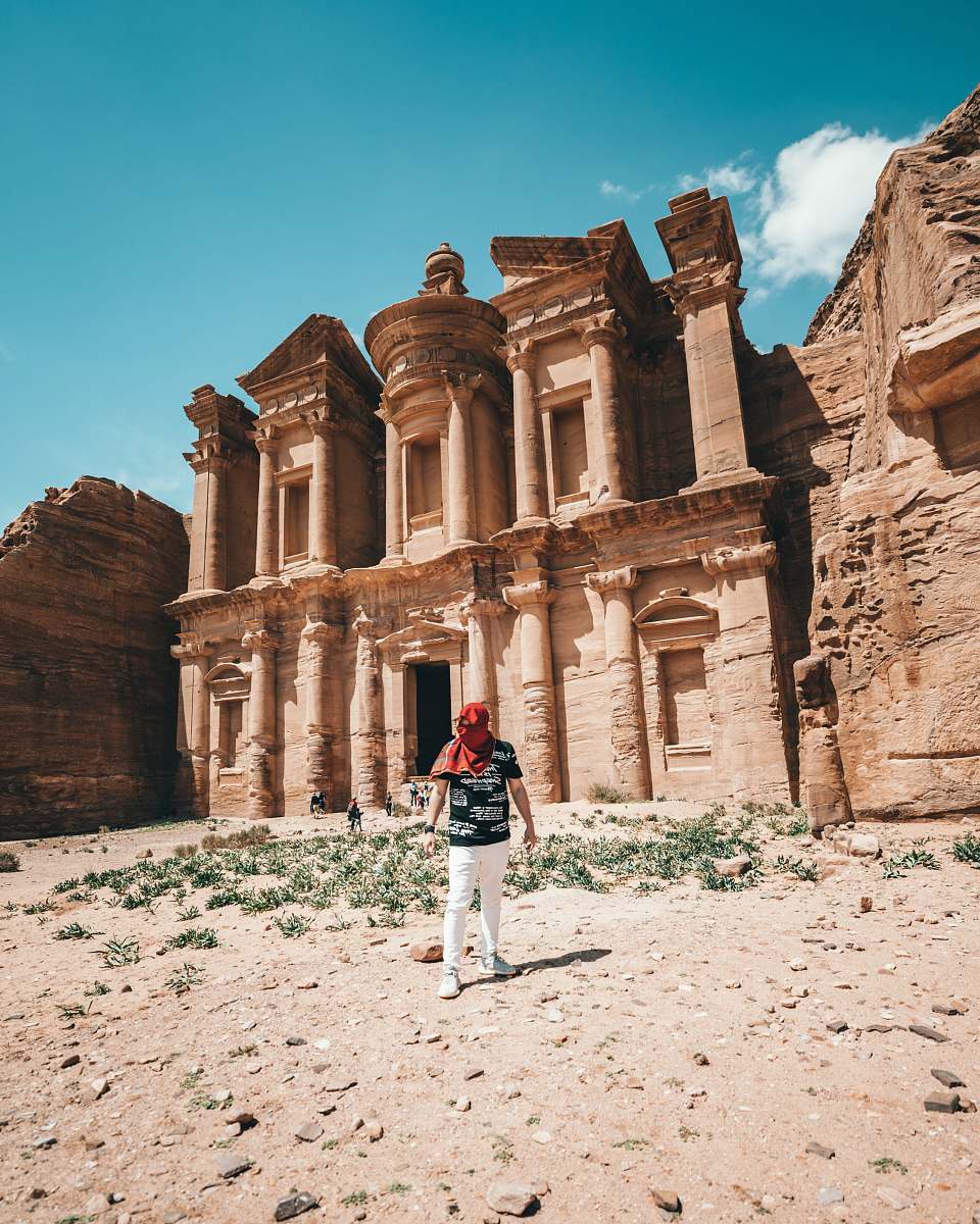 building man standing beside Petra at daytime monastery