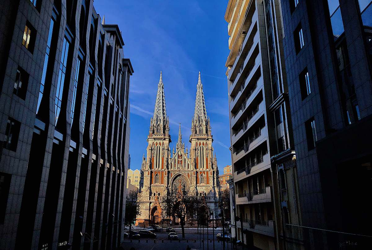 building narrow road in between buildings at daytime spire