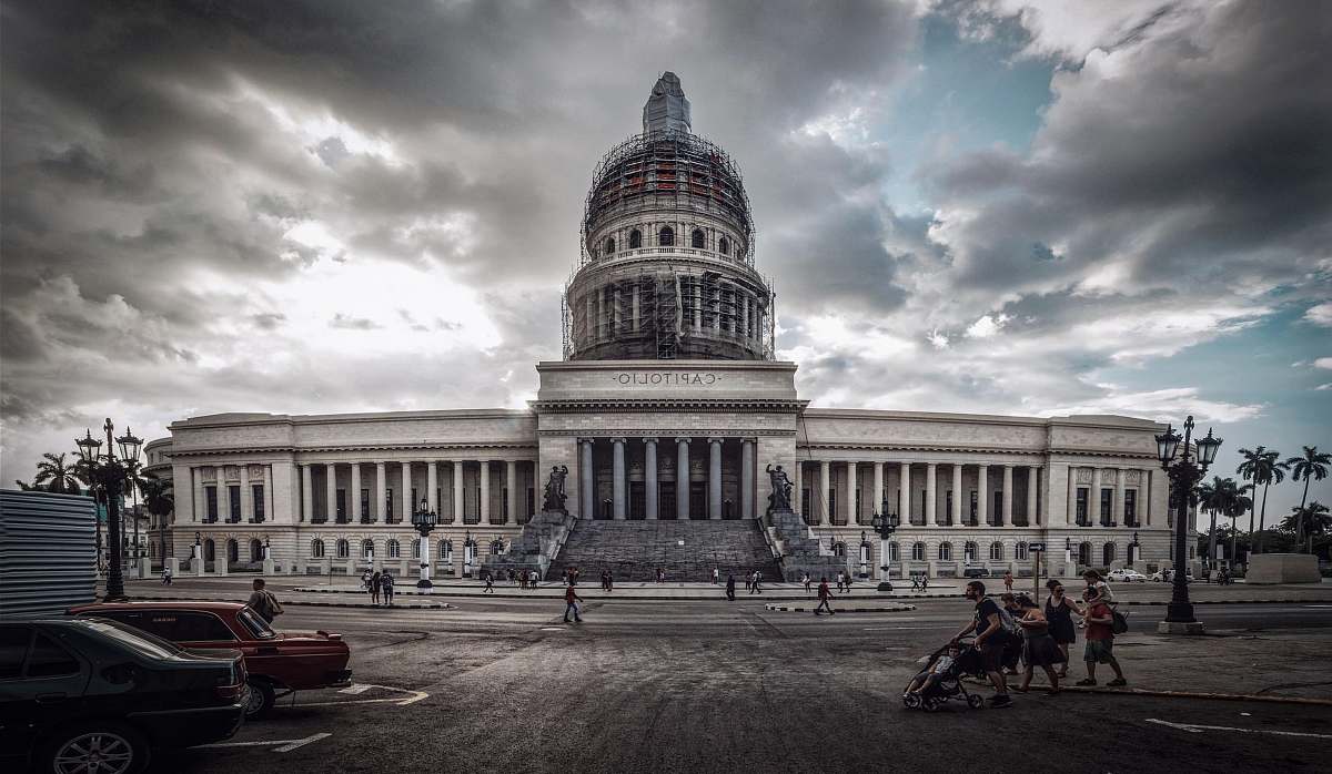 building people and cars in front of building dome