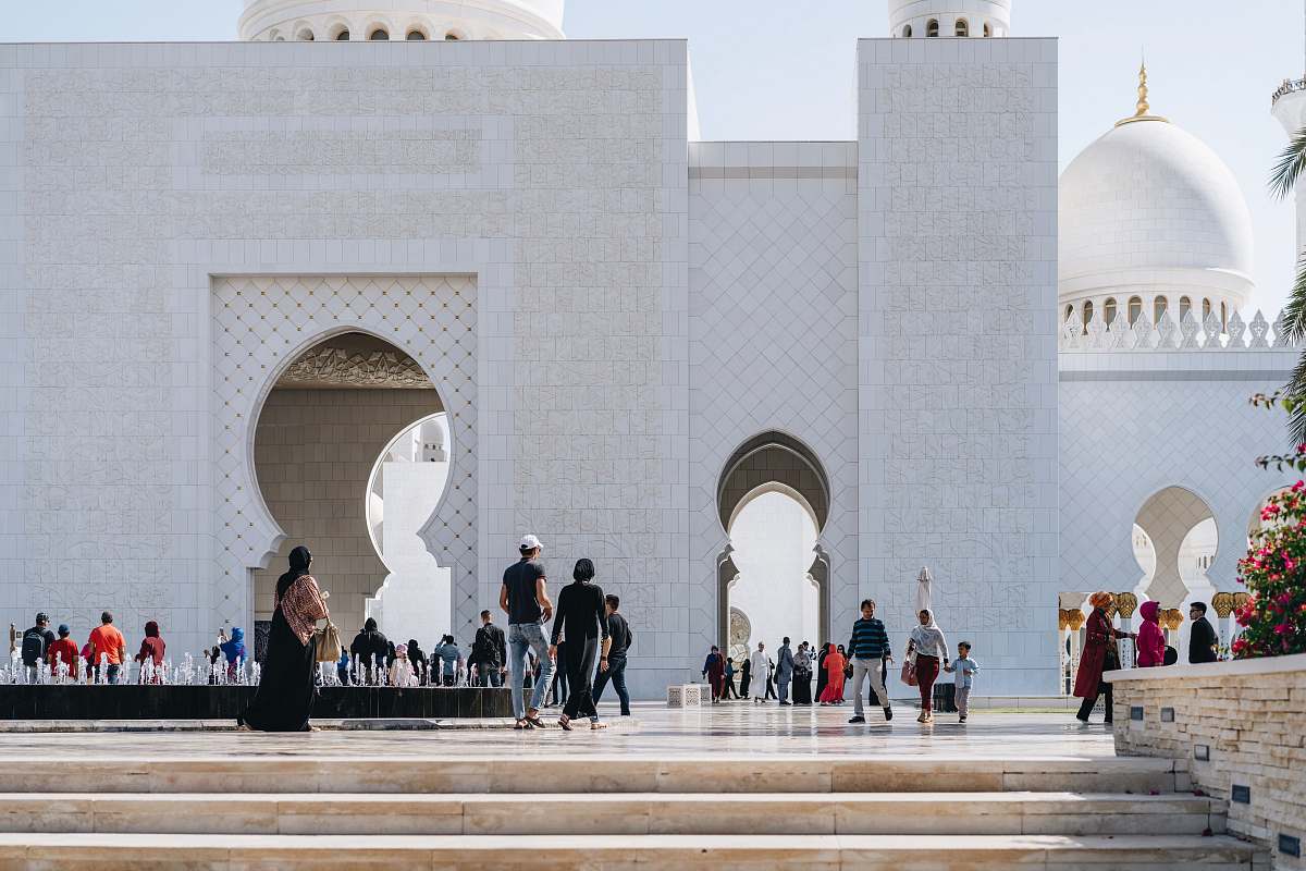 building people walking beside white mosque walls dome