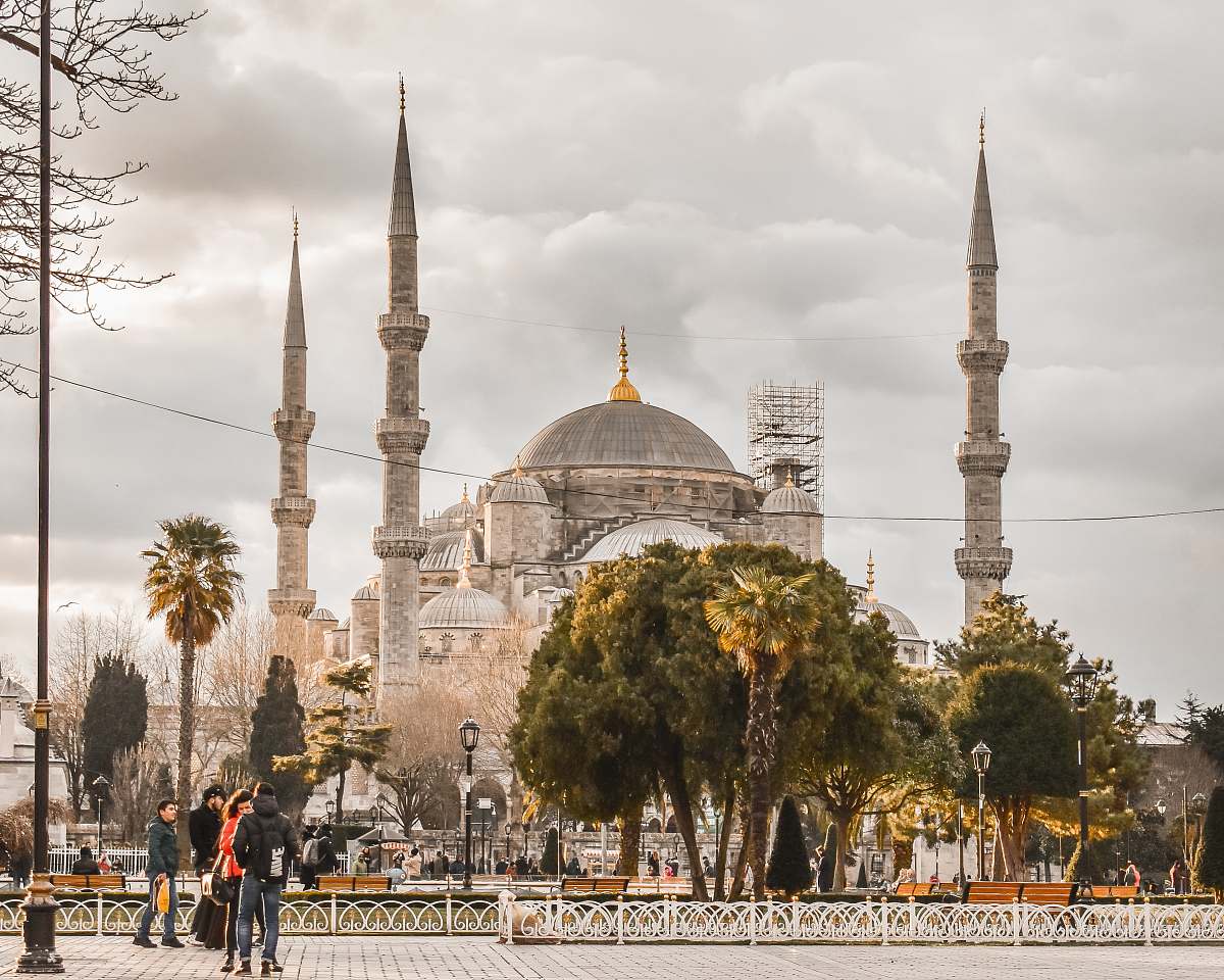 building people walking near trees and Blue Mosque dome