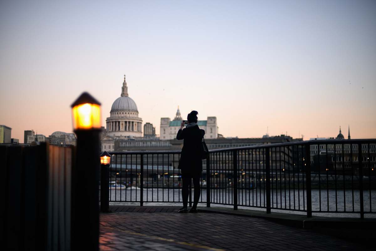 building person by the metal fence standing and overlooking white building dome