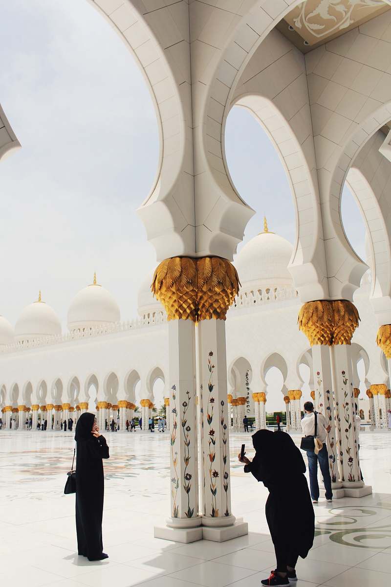 building person taking picture of woman wearing abaya and hijab during daytime dome
