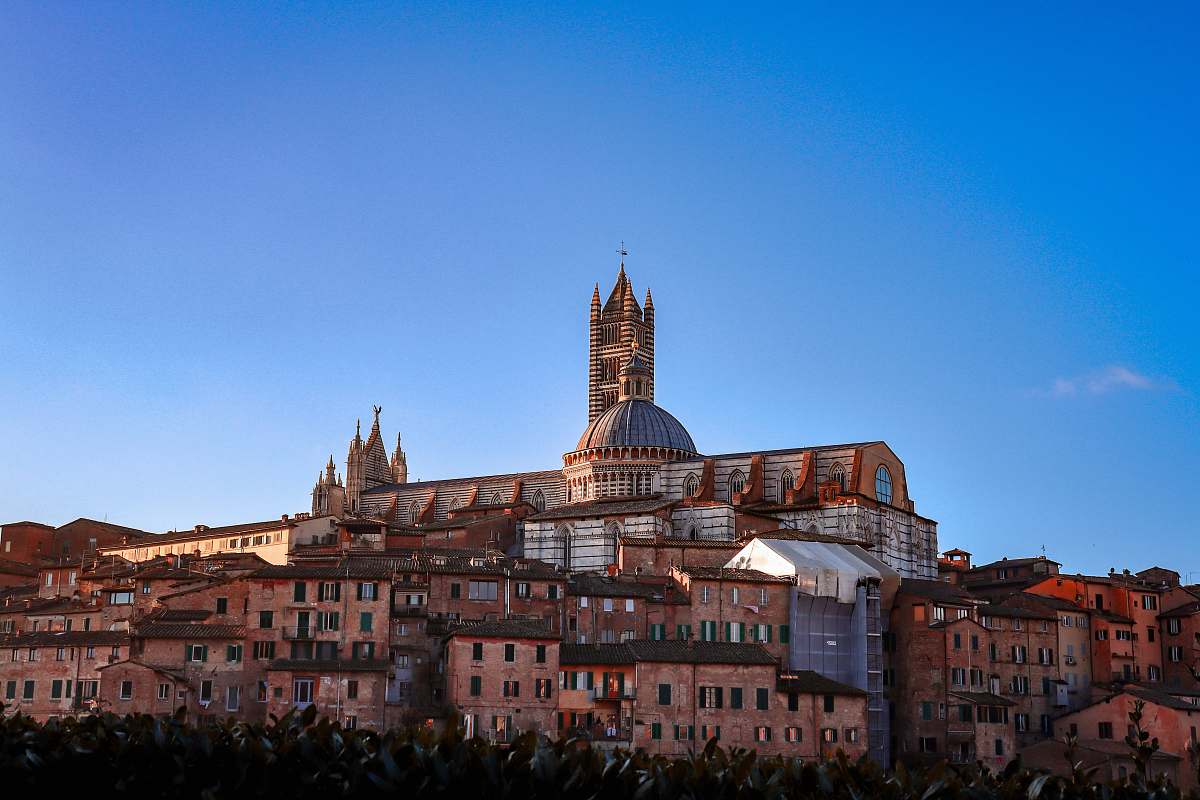 building Siena Cathedral in Italy under blue and white sky spire