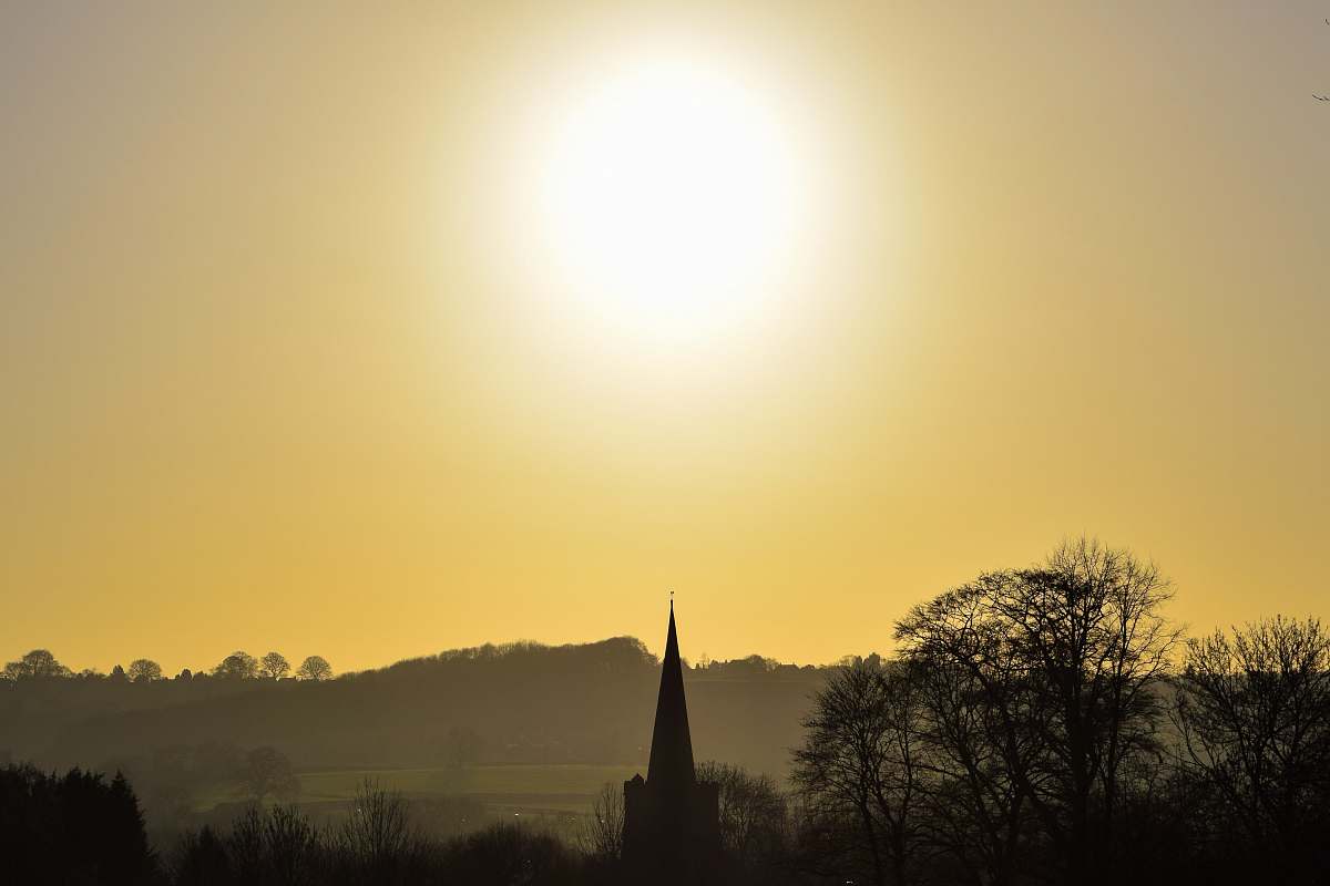 building sun above trees spire