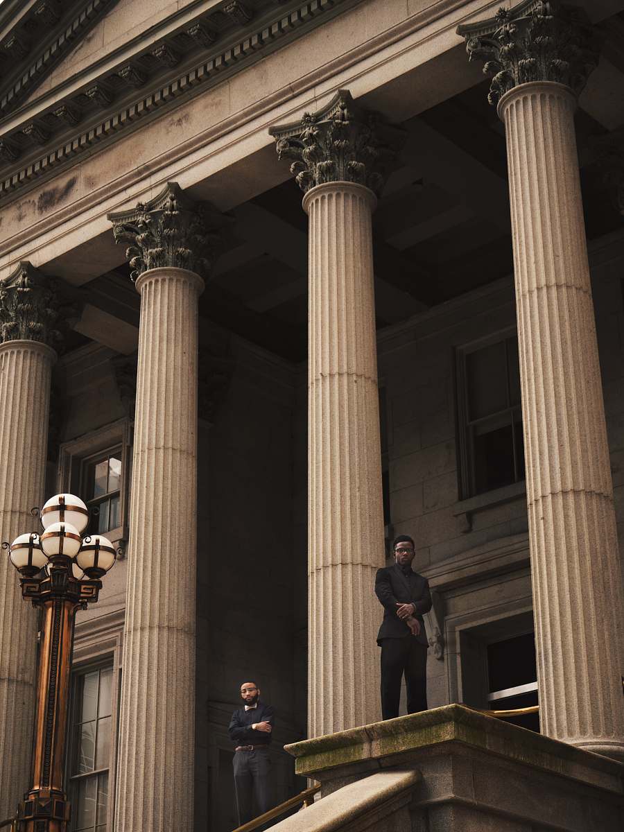building two men standing on Corinthian column building pillar