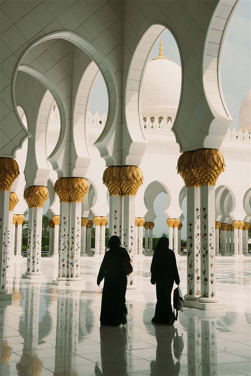 building two women standing near white pillars dome