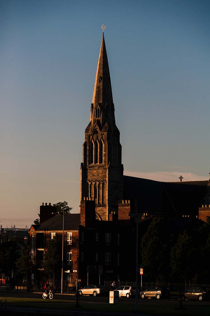 building vehicles parking near brown castle under blue and white sky during daytime spire