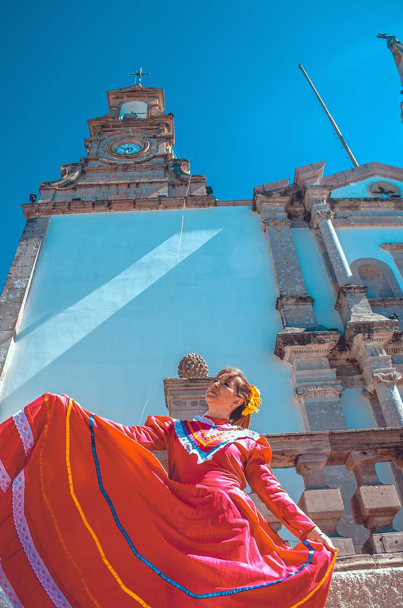 building woman wearing orange dress near church tower