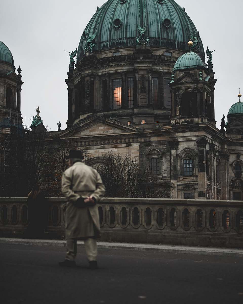 dome man walking on bridge near brown concrete dome building architecture