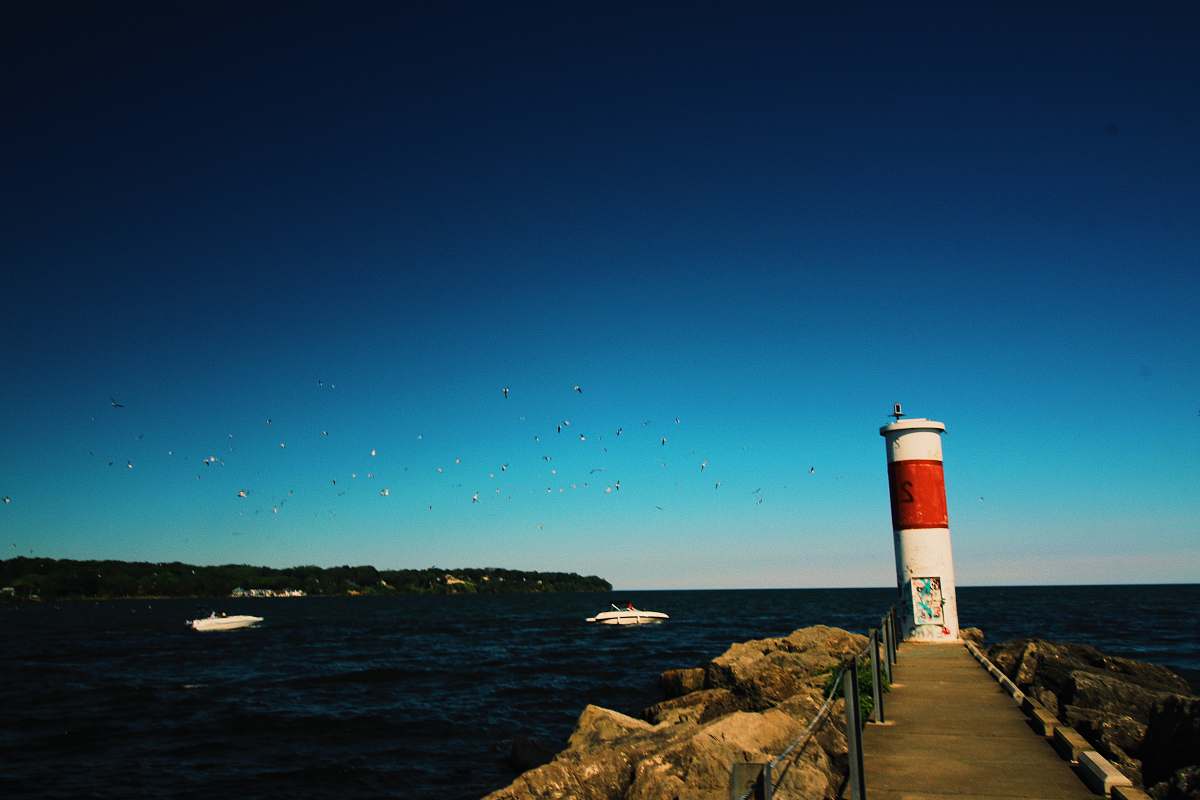 architecture white and red lighthouse near pathway beside rock formation viewing blue sea lighthouse