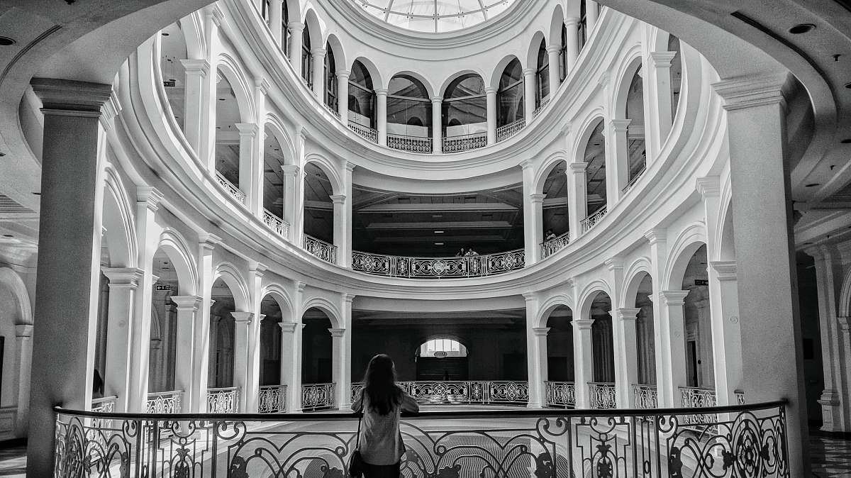 architecture woman standing beside balustrade black-and-white