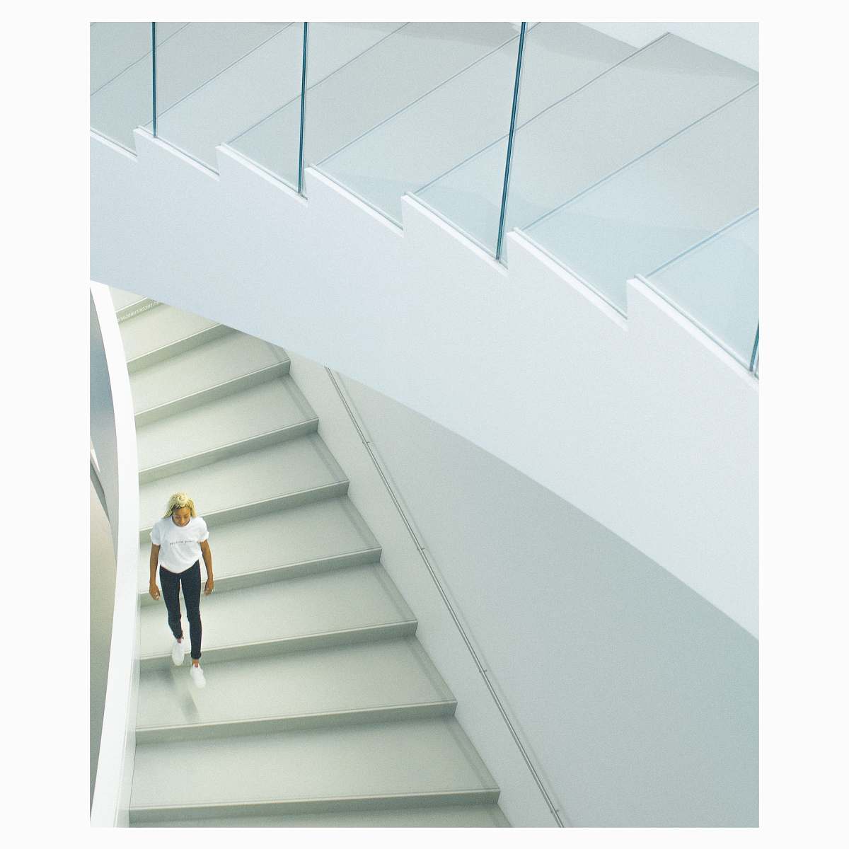 staircase woman wearing white crew-neck t-shirt walking on stairs banister