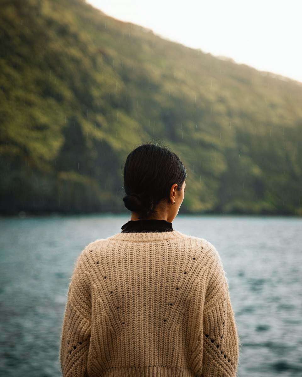 clothing man in brown knit sweater standing near body of water during daytime sweater