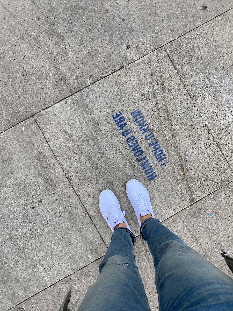 clothing person in blue denim jeans and white sneakers standing on gray concrete floor footwear