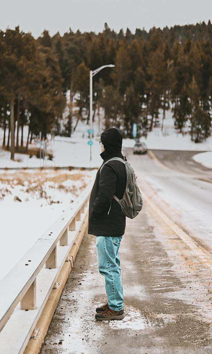 clothing person standing on road's guard rail during daytime footwear