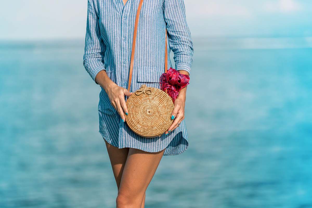 purse woman wearing blue and white striped dress shirt dress with brown wicker crossbody bag near sea at daytime los angeles