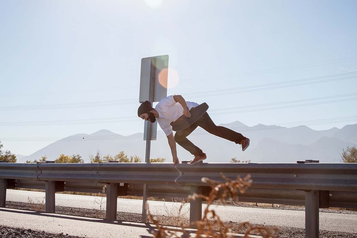 jump man crossing on road fence while holding black skateboard utah lake