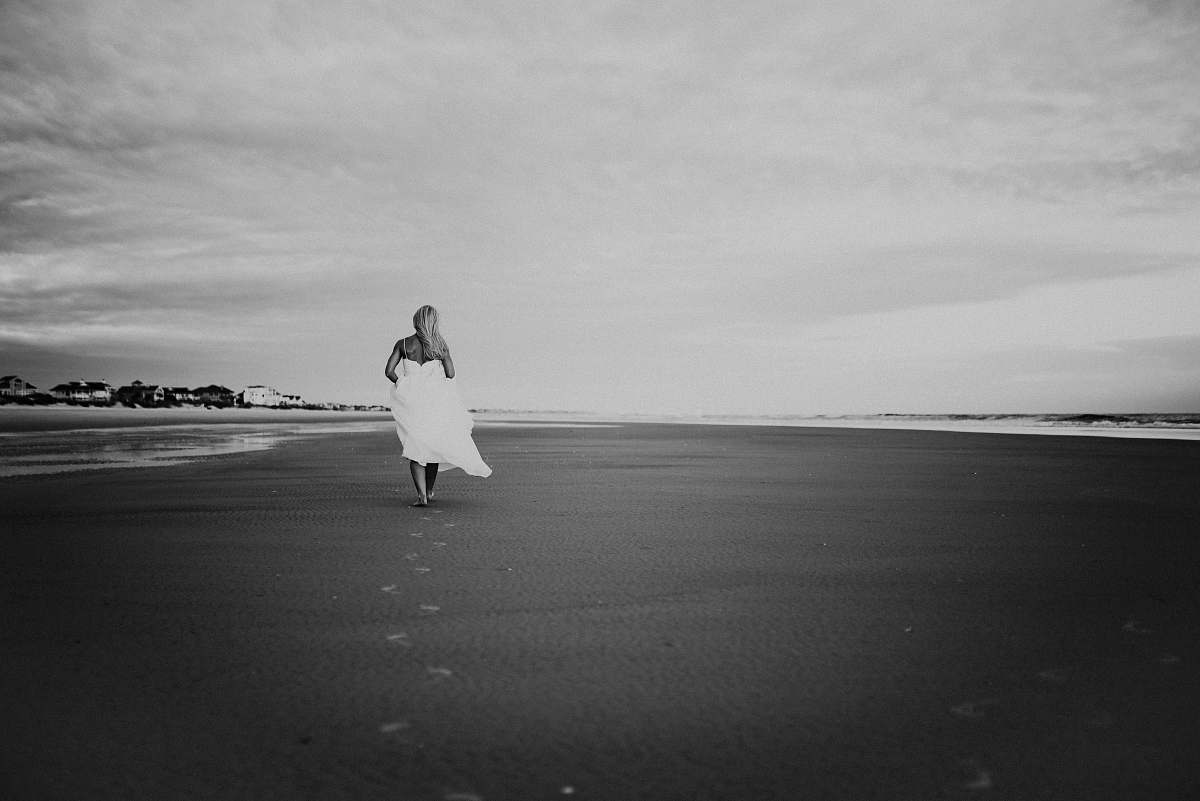black-and-white grayscale photo of woman walking on seashore grey