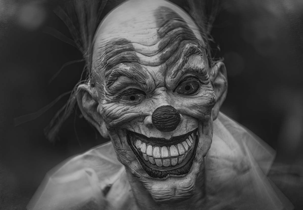 human grayscale photography of person wearing clown mask grey