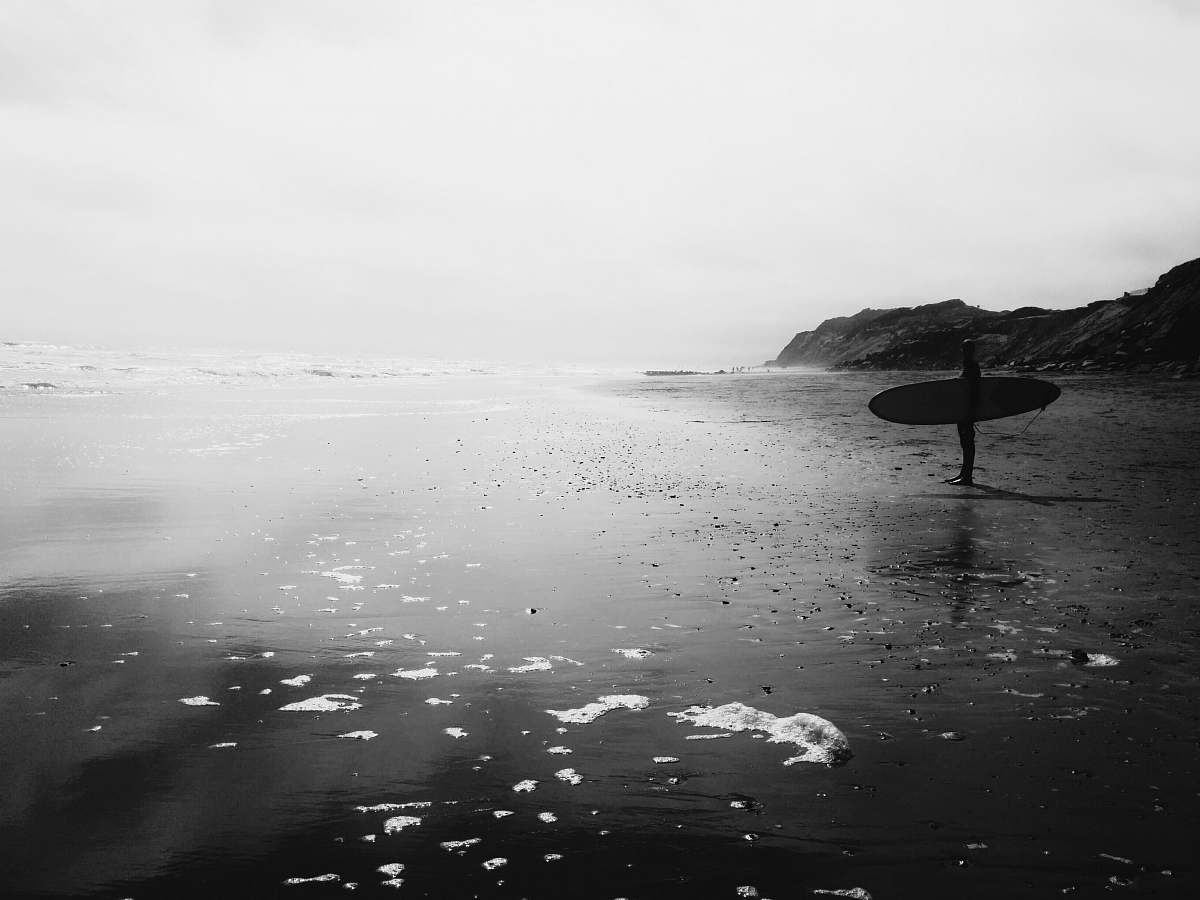 grey man holding skimboard near sea ocean