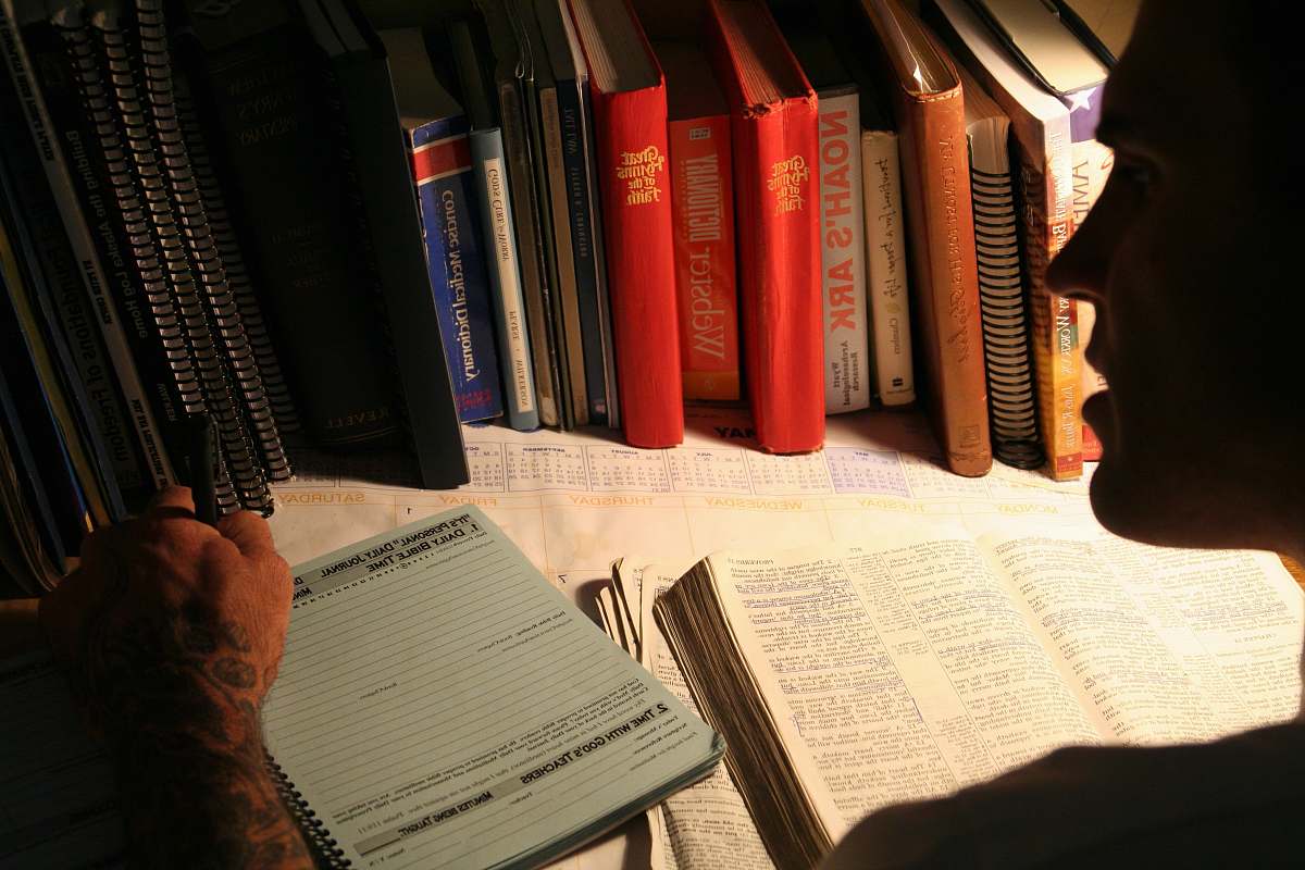 bible man writing in front of books journal