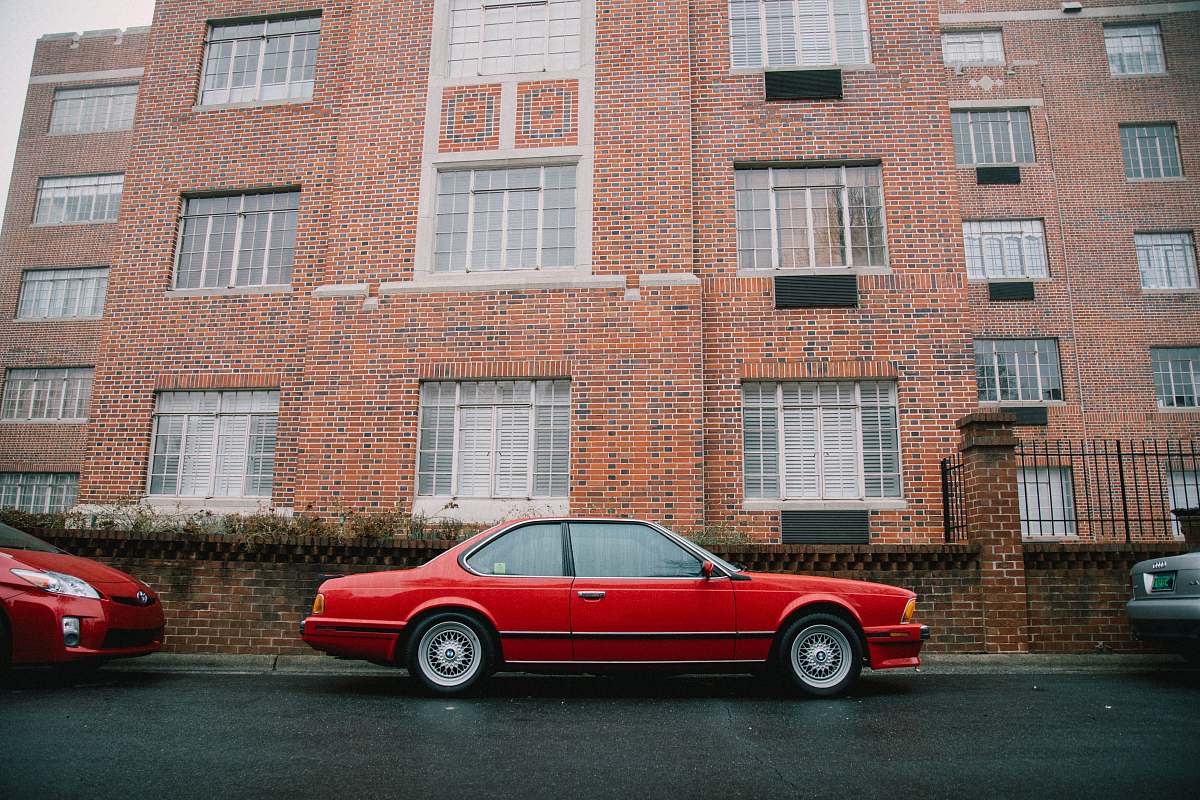 car red coupe parked beside brown building automobile