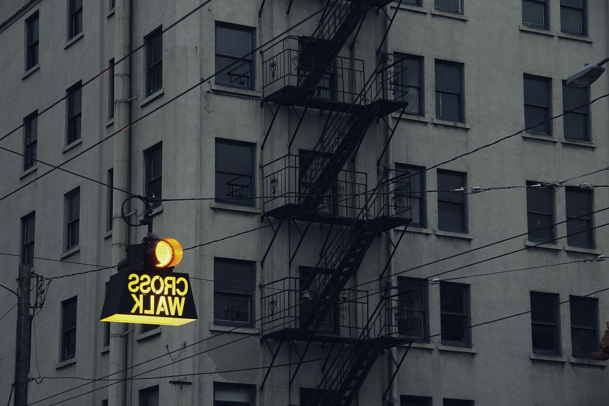 window lighted Cross Walk street signage near concrete building curtain