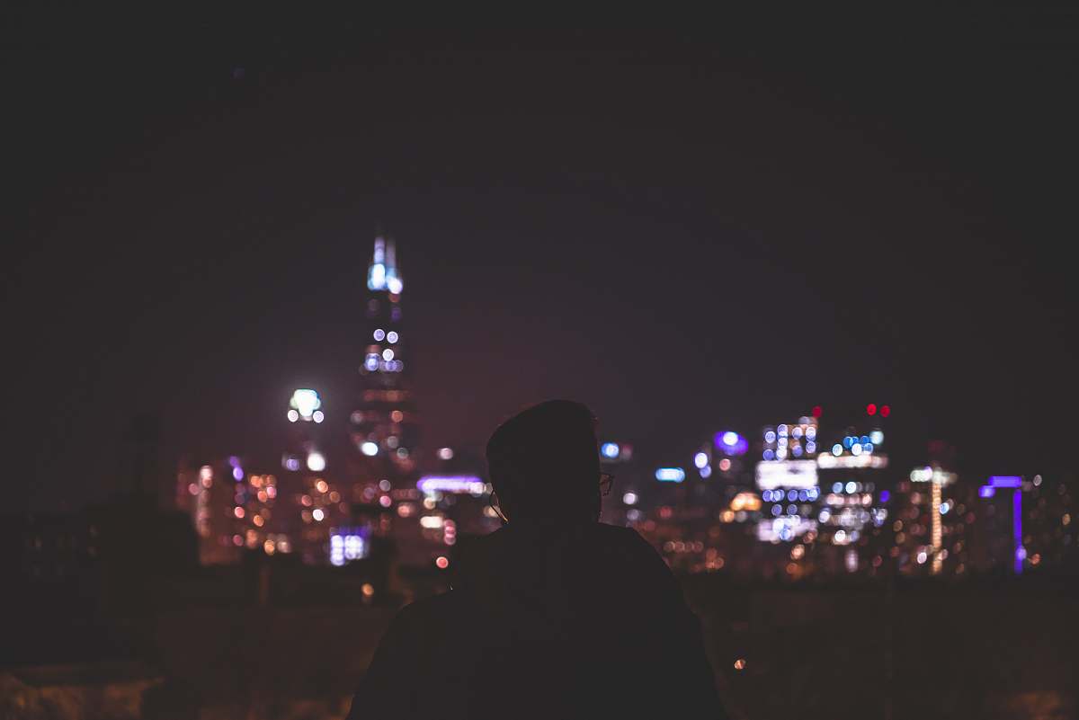 human man in black hoodie standing near city buildings during night time person