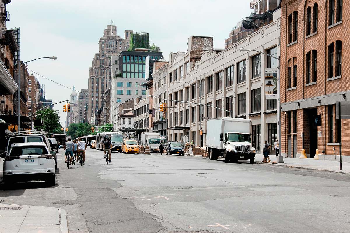 road people walking and riding bike in front of high-rise buildings during daytime street