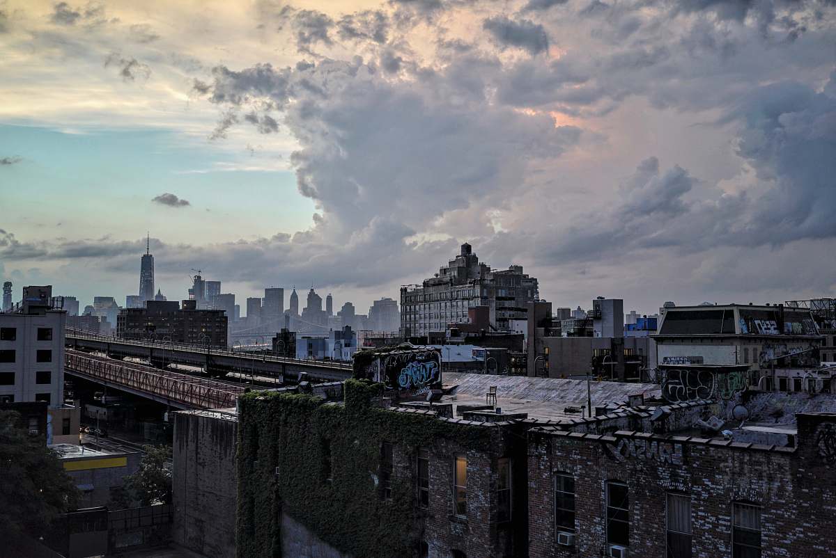 city photo of black concrete building under white clouds at noontime urban