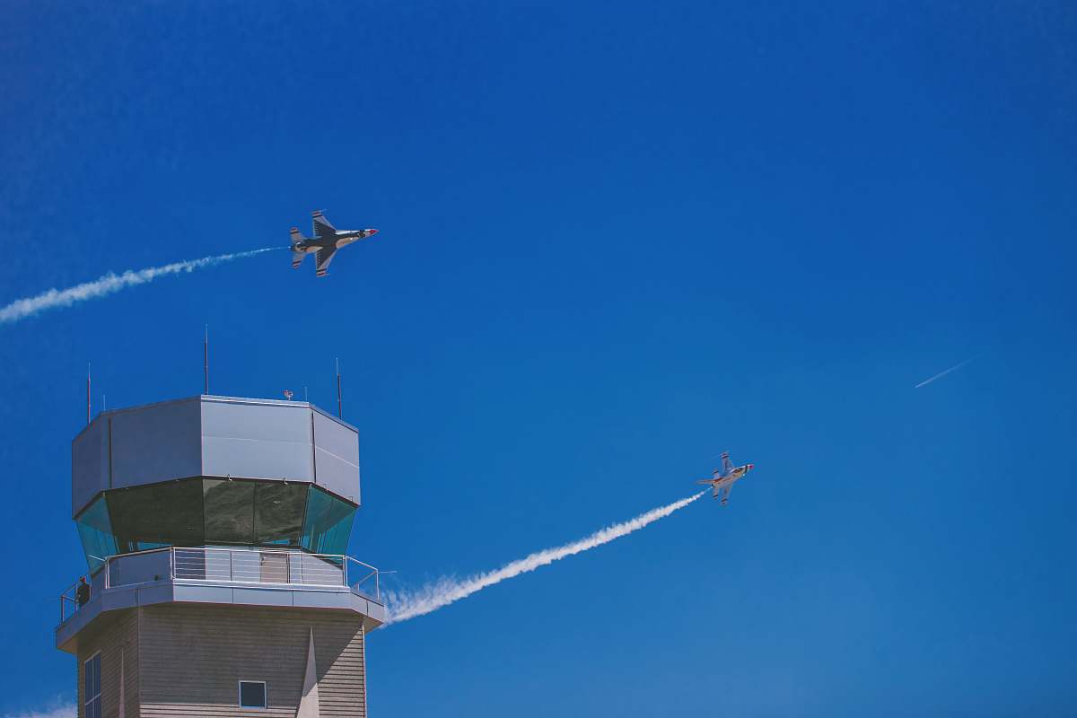 architecture two jet planes flying over gray building during daytime tower