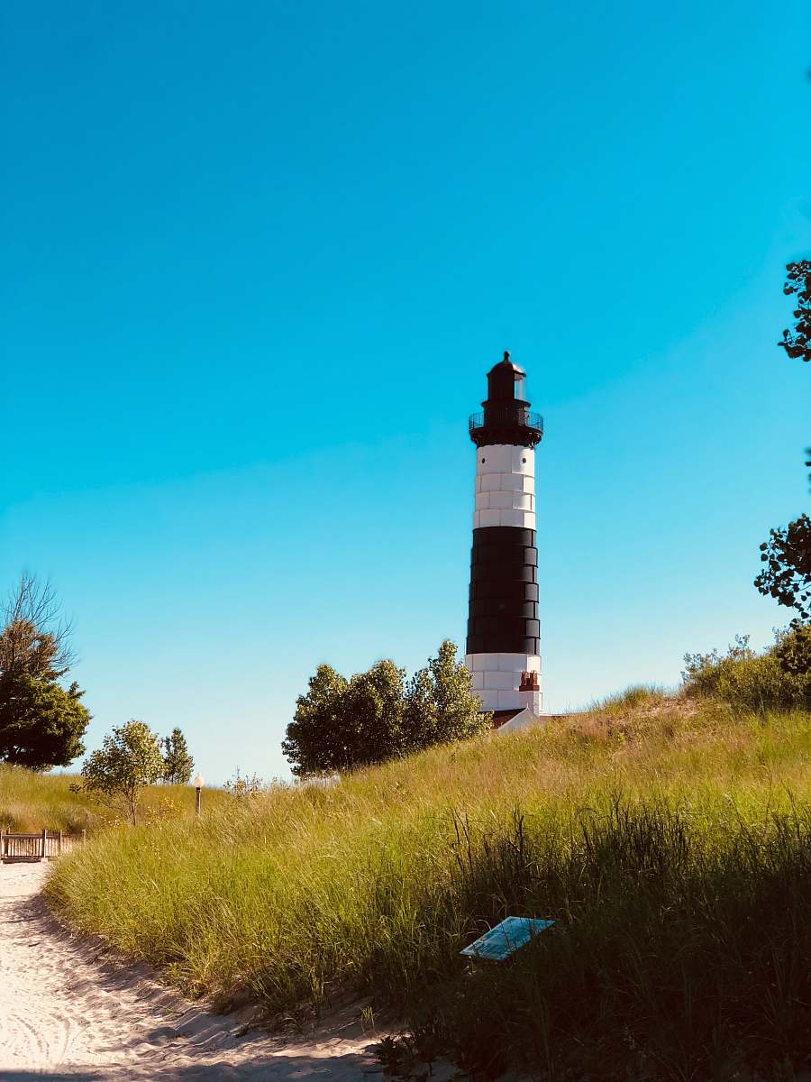 architecture white and black lighthouse on green grass field under blue sky during daytime tower