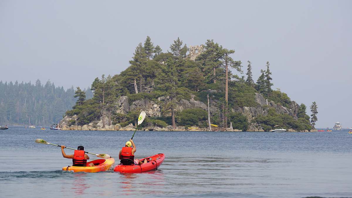 boat two person kayaking on water near islet kayak