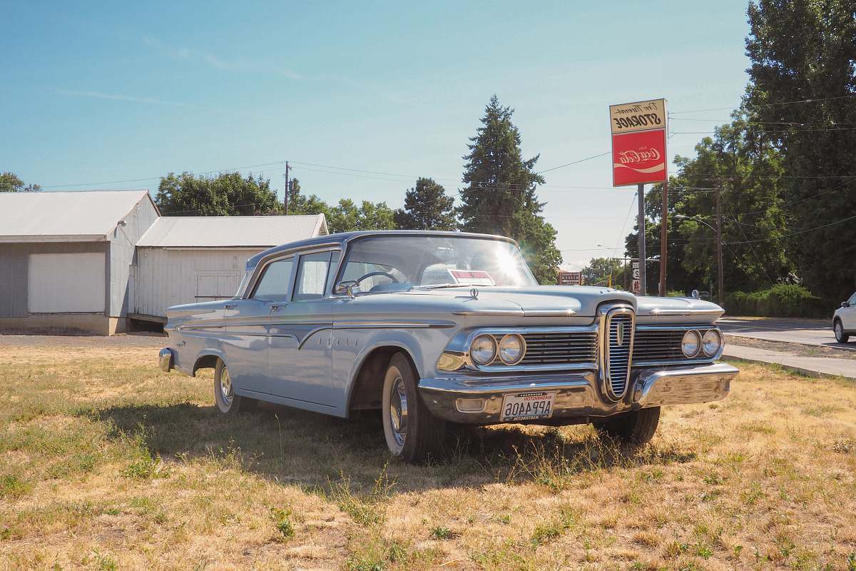 building classic teal sedan near house during daytime tree