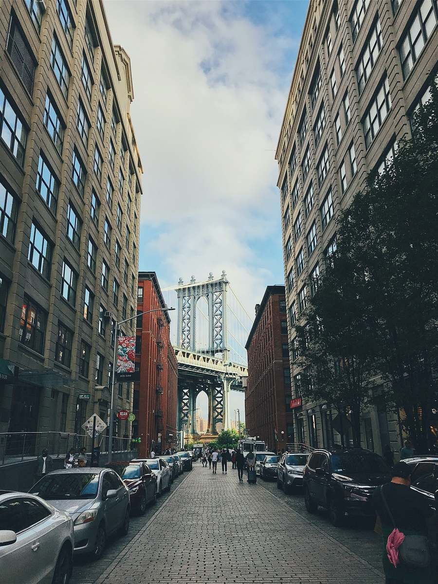 city group of people walked in street in front of Manhattan bridge vehicle