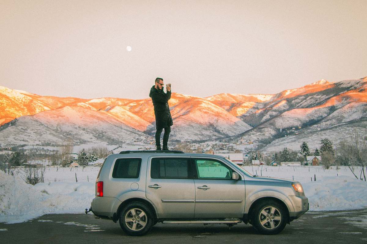 vehicle man standing on top of SUV midway