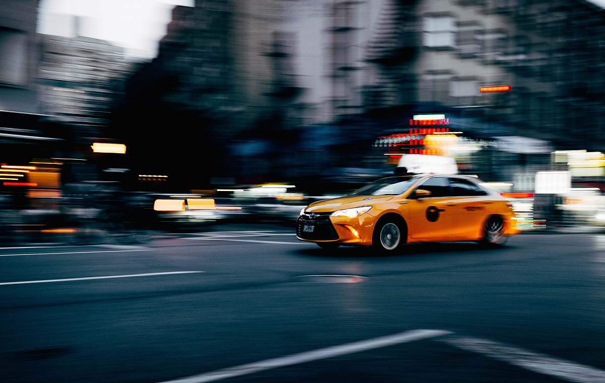 cab orange coupe running on gray street during daytiem taxi