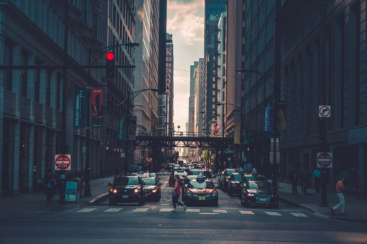 urban woman crossing pedestrian lane towards building during daytime chicago