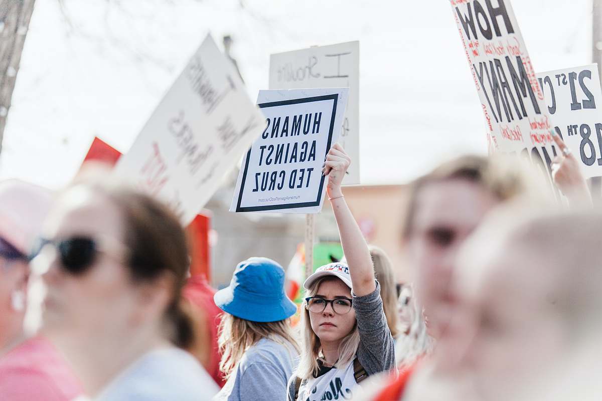politics woman holding Humans Against Ted Cruz signage during daytime government