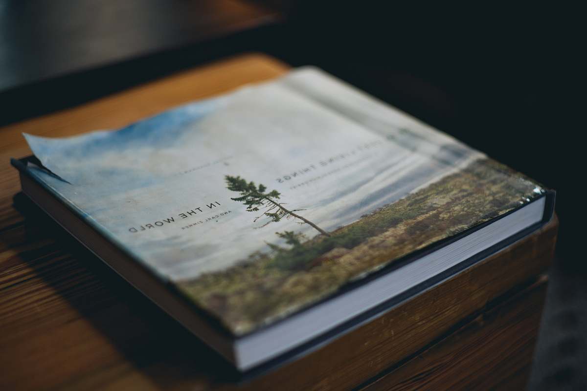 This captivating image features a softbound book in white and brown hues elegantly positioned atop a rustic brown wooden container. Shot at a cozy hotel near the iconic Brooklyn Bridge, this scene evokes a sense of warmth and tranquility. Ideal for use in lifestyle blogs, travel articles, or as decor inspiration for hotels and cafes, this photograph beautifully blends hospitality and literary charm.