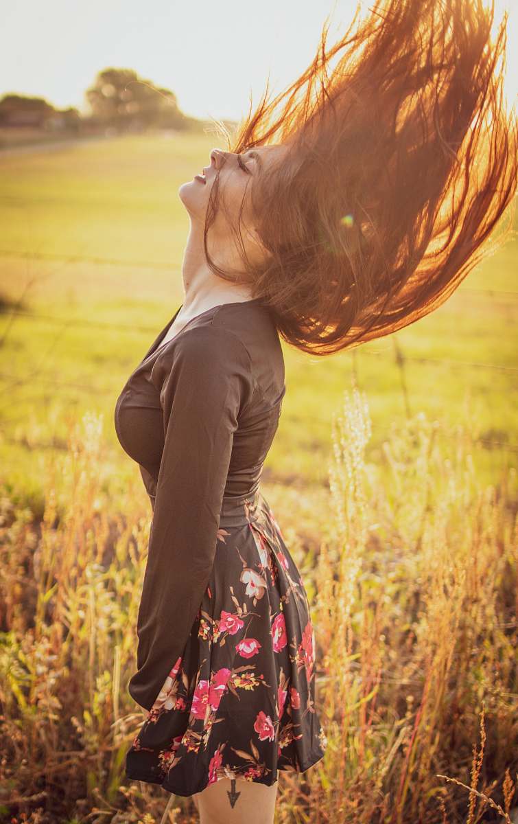apparel woman in black long-sleeved top and black and red floral mini skirt standing in grass field clothing
