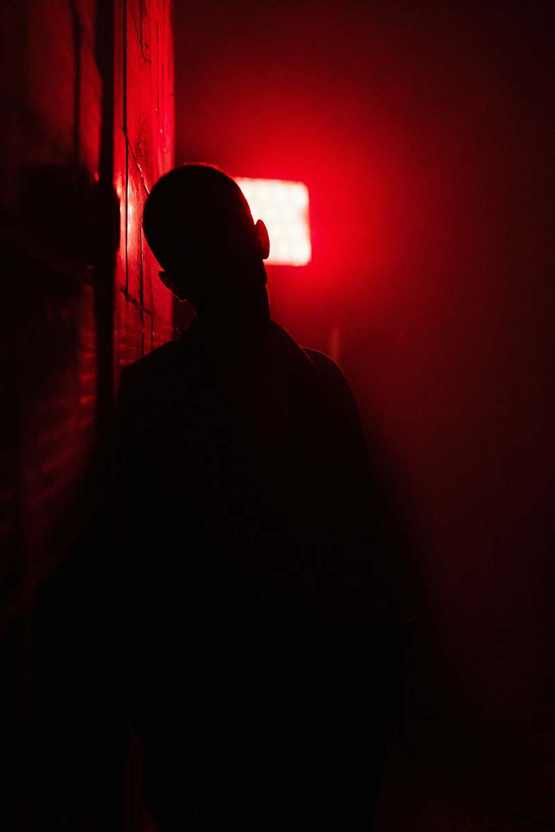 light man in black shirt standing near red light human