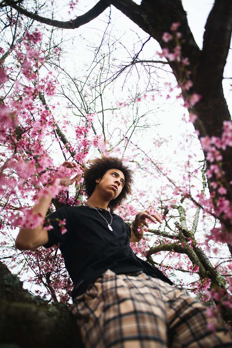 plant man wearing black and brown plaid shorts and black shirt cherry blossom