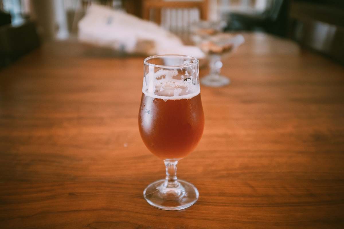 beer clear wine glass with brown liquid on brown wooden table alcohol