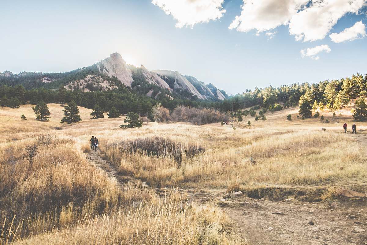 boulder brown grass field near gray mountain under white sky field