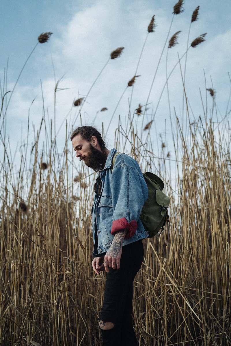 plant man in blue and gray hoodie standing on green grass field during daytime lawn