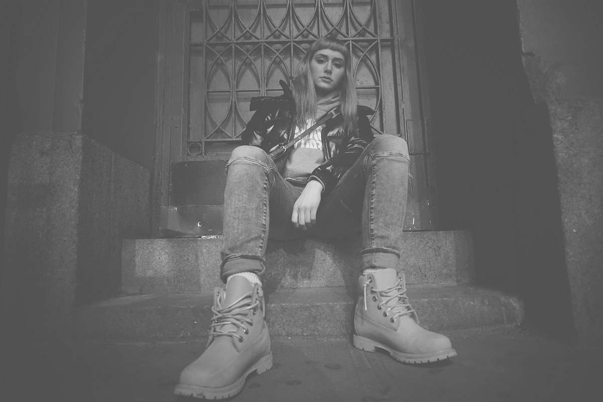 black-and-white grayscale photo of woman sitting on concrete stair soho