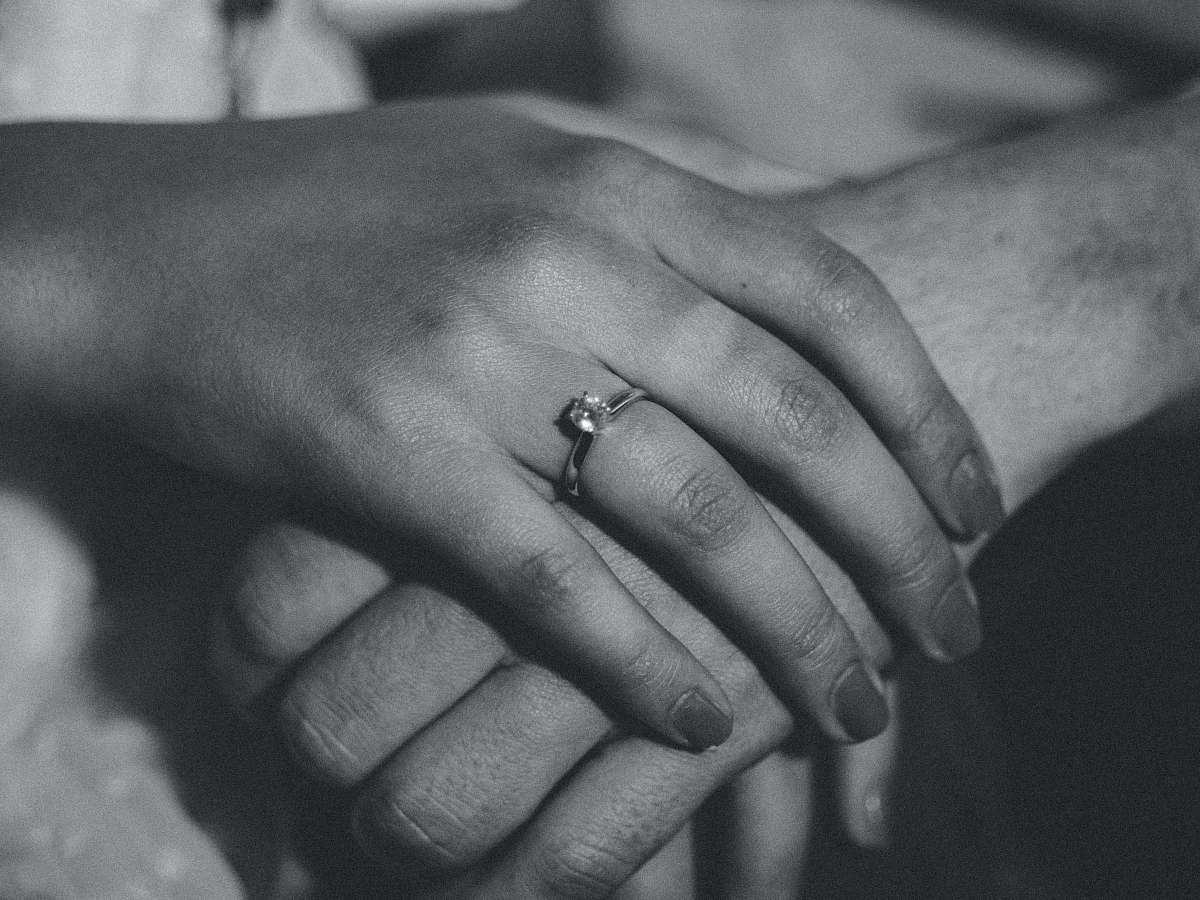 black-and-white grayscale photography of human hands holding together ring