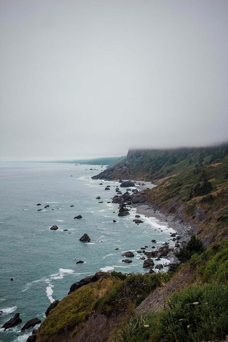 promontory landscape photography of body of water splashing on rocks water